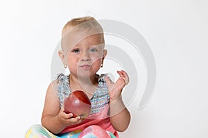 Sitting cool toddler girl is holding red apple