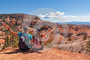 Bryce Canyon - Sitting couple with scenic aerial view from Fairyland hiking trail on massive hoodoo sandstone rock formations