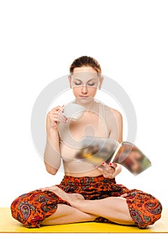 Sitting female yogi drinking and reading