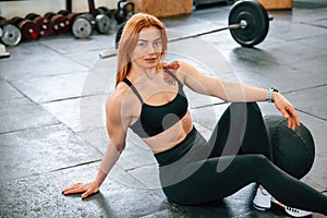 Sitting on the floor. Beautiful strong woman is in the gym