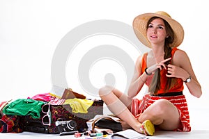 Sitting girl near overfilled suitcase.