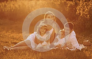 Sitting on the grass. Father, mother with daughter and son spending free time outdoors at sunny day time of summer