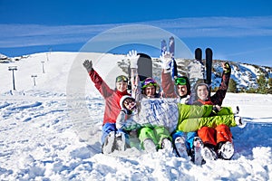 Sitting happy friends with snowboards having fun