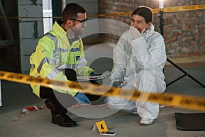 Sitting and laughing. Two detectives are collecting evidence in a crime scene. Forensic specialists are making expertise