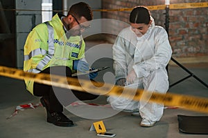 Sitting and laughing. Two detectives are collecting evidence in a crime scene. Forensic specialists are making expertise