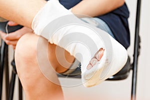 Sitting man leg injury plaster,  ankle