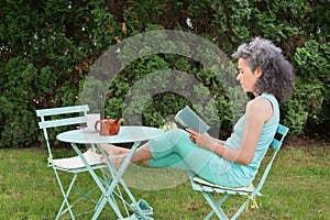 Sitting woman reading in her garden Relaxing Cup and Teapot