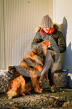 Sitting woman with red hair stroking his dog