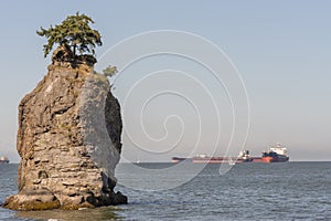 Siwash Rock with huge waiting sea vessels.