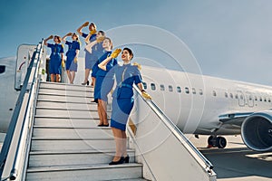 Six air hostesses saluting before the take-off
