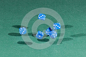 Six blue dices falling on a green table