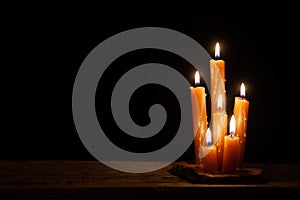 Six burning candles against a black background.