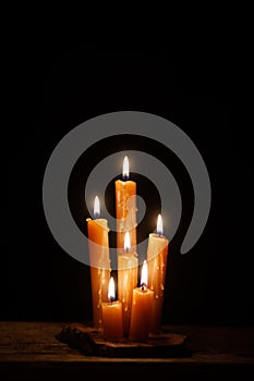 Six burning candles against a black background.