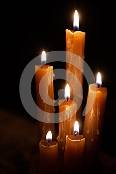 Six burning candles against a black background.