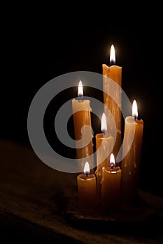 Six burning candles against a black background.