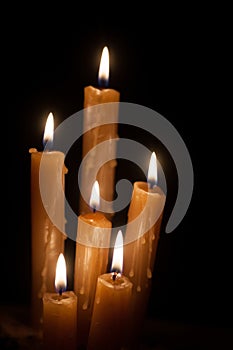 Six burning candles against a black background.
