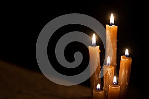 Six burning candles against a black background.