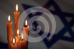 Six burning candles on Israel flag background.