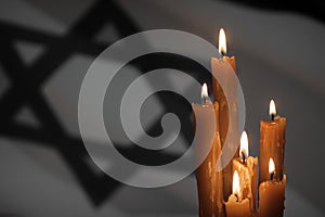 Six burning candles on Israel flag background.