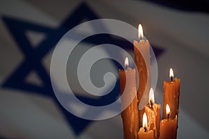 Six burning candles on Israel flag background.