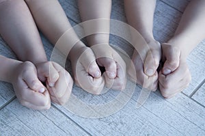 Six children`s hands clenched into fists. On a wooden background.