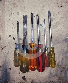 Six colorful screwdrivers lined up on a work surface.