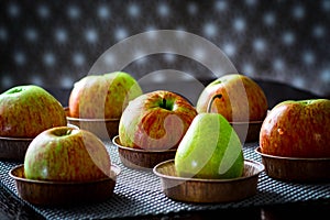 Six country apples and one pear on a brown table