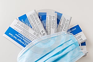 Six Covid-19 rapid antigen tests with german labeling and a protective mask on white background