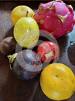 Six different of fruit, namely dragon fruit, oranges, snake fruit, passion fruit, water guava, mangosteen fruit on a brown table.