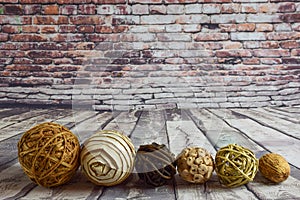 Six different types, colors and composition of wicker decorative balls lie in a row on a wooden old background and a brick wall