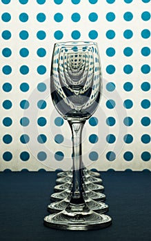 Glasses for liqueur standing in line and white background with blue spots.