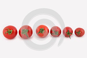 Six fresh cherry tomatoes lie in a row from the largest to the smaller. Tomatoes isolated on white background.