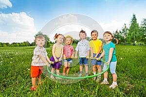 Six funny children holding one hoop together