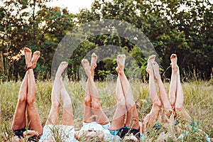 Six girls lie on the grass and raise their legs up