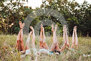 Six girls lie on the grass and raise their legs up