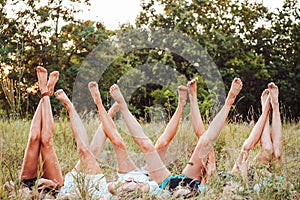 Six girls lie on the grass and raise their legs up