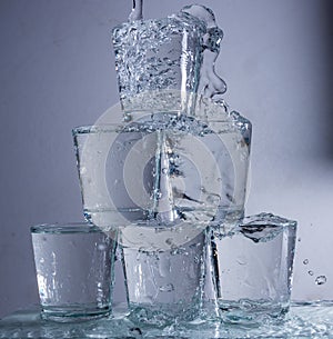 Six glasses stacked by a tower on a multi-colored background