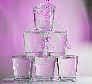 Six glasses stacked by a tower on a multi-colored background