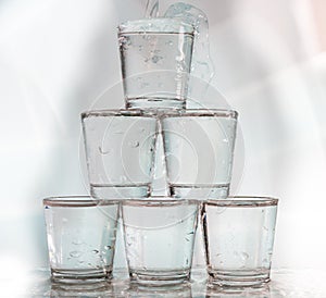 Six glasses stacked by a tower on a multi-colored background