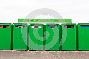 Six green recycling bins by recycling point to collect rubbish