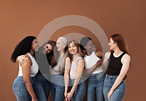 Six laughing women of different body types and ethnicities in studio. Group portrait of smiling females standing together against