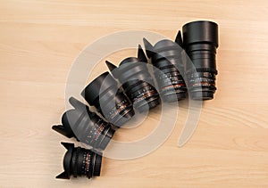 Six lenses with different focal lengths lie on a wooden surface. Filming using DSLR cameras