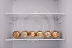 Six metal beer cans inside in empty clean refrigerator