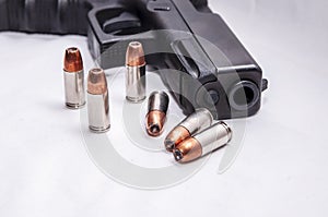 Six 9mm hollow point bullets in front of a black 9mm pistol