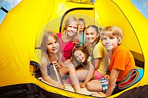 Six nice kids looking from camping tent