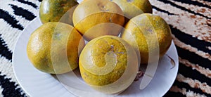 Six oranges on a white plate