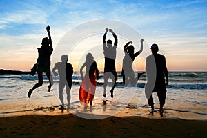 Six people jumping on beach at sunset.