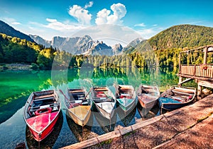 Six pleasure boats on Fusine lake. Bright morning scene of Julian Alps with Mangart peak on background, Province of Udine, Italy,
