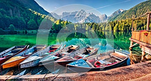 Six pleasure boats on Fusine lake. Calm morning view of Julian Alps with Mangart peak on background, Province of Udine, Italy, Eur