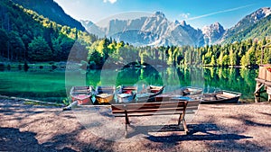 Six pleasure boats on Fusine lake. Spectacular morning scene of Julian Alps with Mangart peak on background, Province of Udine, It